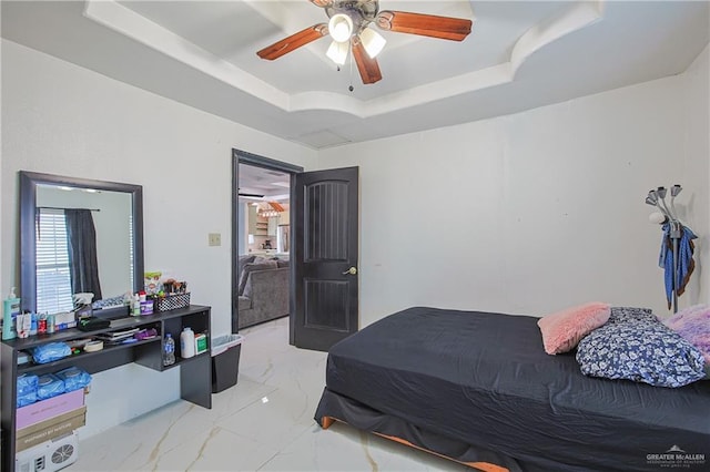 bedroom with ceiling fan and a raised ceiling