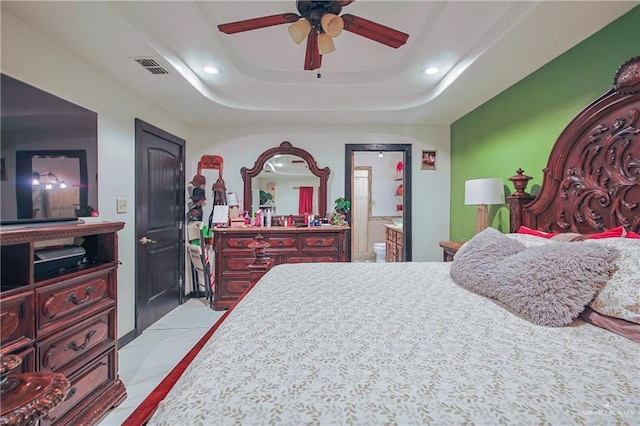 bedroom featuring ceiling fan, ensuite bathroom, and a tray ceiling