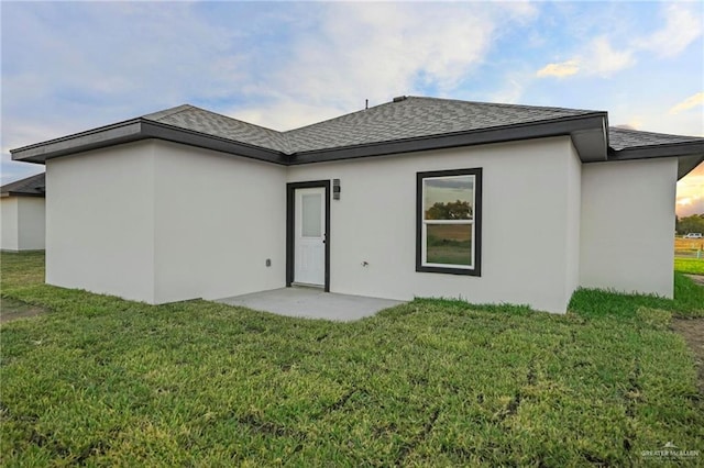 back of property with a lawn and a patio area