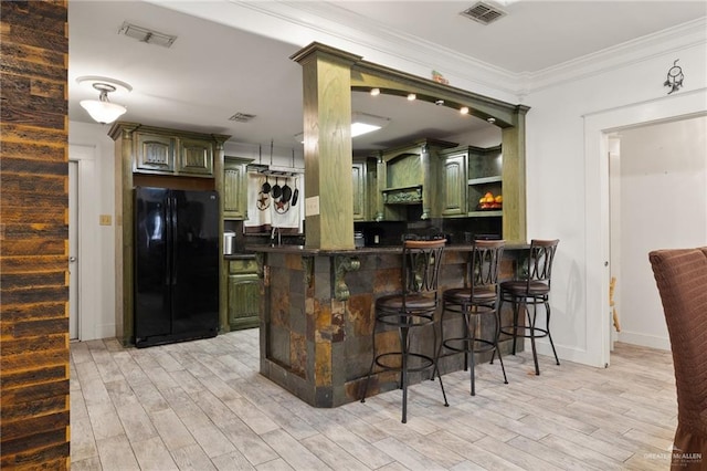 bar featuring black refrigerator, green cabinets, and light hardwood / wood-style floors