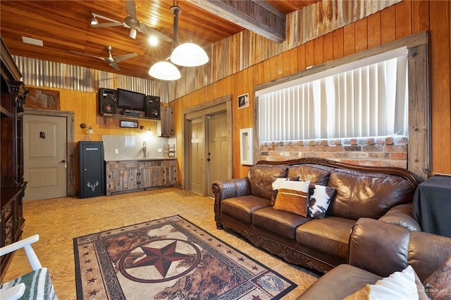 living room featuring ceiling fan, wooden walls, beam ceiling, light tile patterned floors, and wooden ceiling