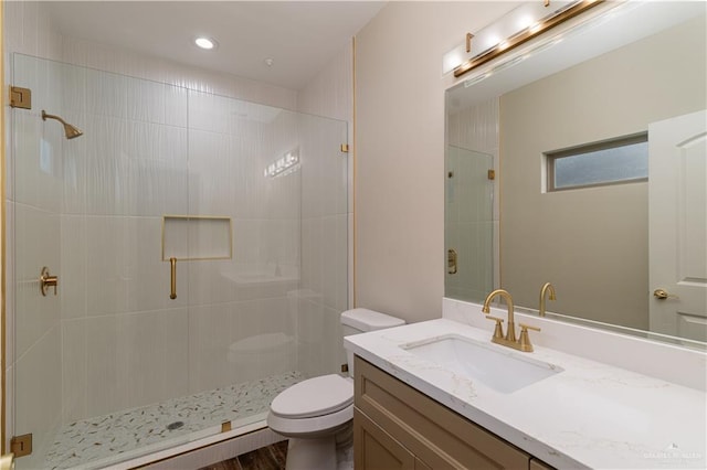 bathroom featuring vanity, toilet, and a shower with door