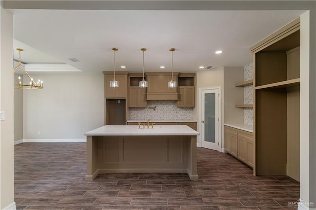 kitchen with a kitchen island with sink, sink, decorative backsplash, and decorative light fixtures