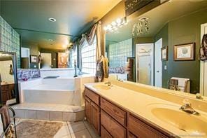 bathroom with tile patterned flooring, vanity, and a relaxing tiled tub