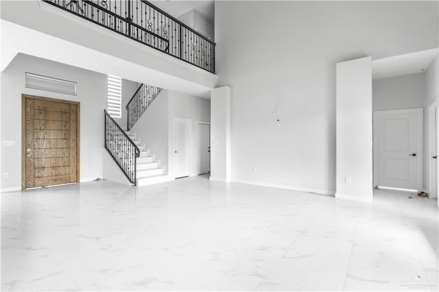 unfurnished living room featuring a high ceiling