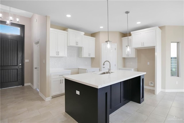 kitchen with white cabinetry, sink, hanging light fixtures, an island with sink, and light tile patterned floors