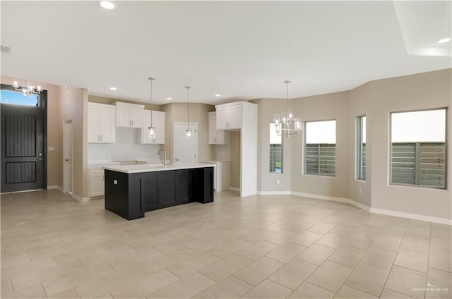 kitchen featuring decorative light fixtures, white cabinetry, a kitchen island with sink, and a chandelier