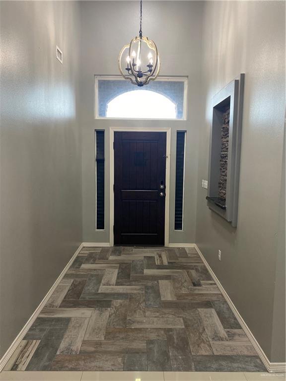 entrance foyer featuring dark parquet floors, a towering ceiling, and a chandelier