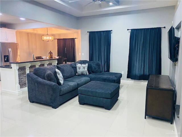 living room with light tile patterned flooring and ceiling fan with notable chandelier