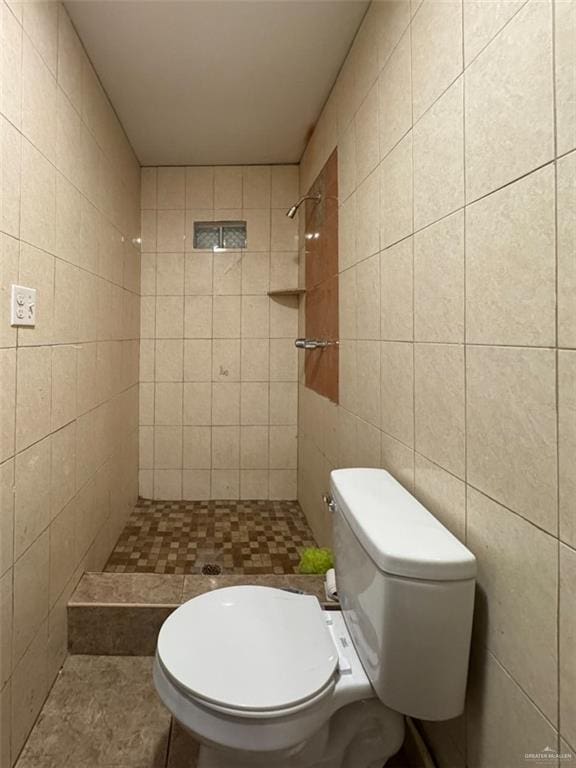 bathroom with tiled shower, toilet, and tile walls