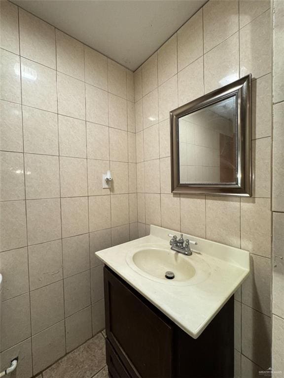 half bath featuring vanity, tile patterned flooring, and tile walls