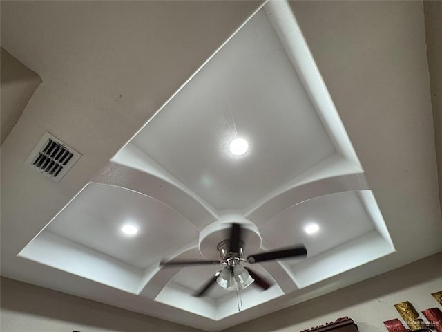 interior details featuring a ceiling fan, a tray ceiling, and visible vents