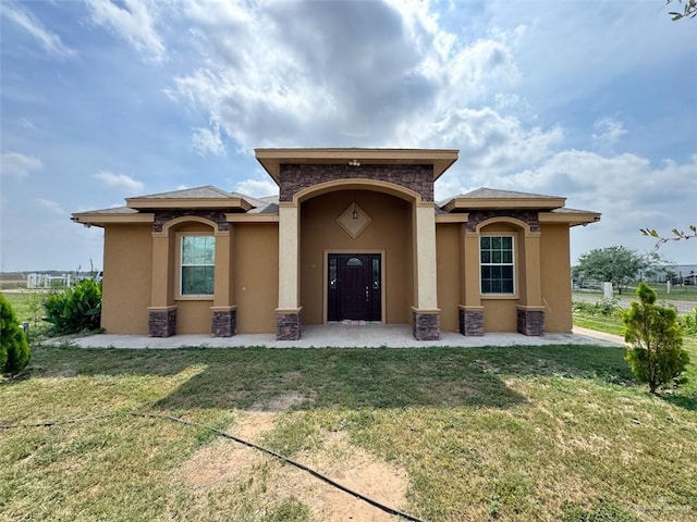 exterior space with stucco siding, a front lawn, and stone siding