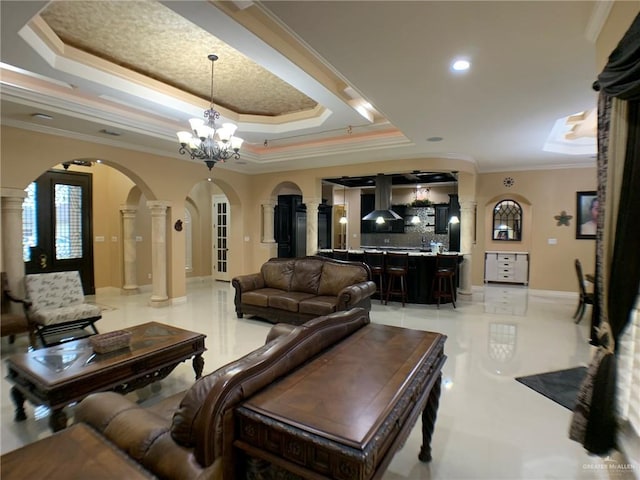 living area featuring crown molding, arched walkways, a raised ceiling, and ornate columns
