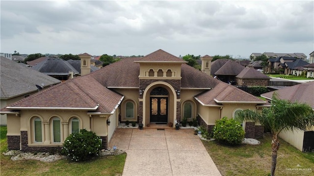 mediterranean / spanish house featuring driveway, a residential view, roof with shingles, stucco siding, and french doors