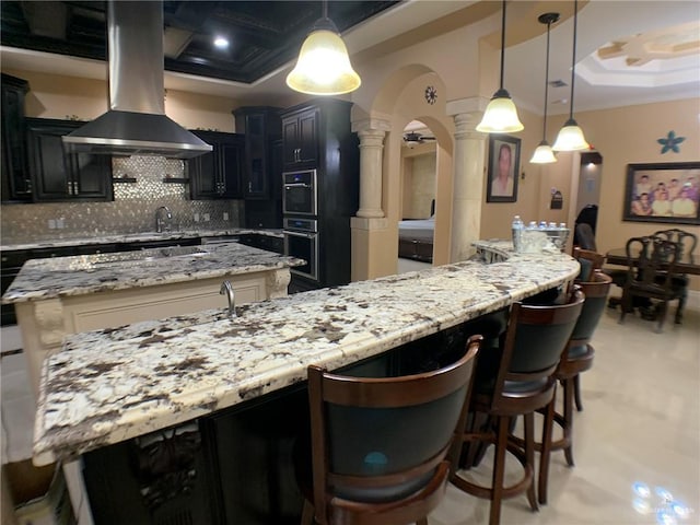 kitchen featuring a kitchen island, coffered ceiling, ornate columns, island exhaust hood, and backsplash