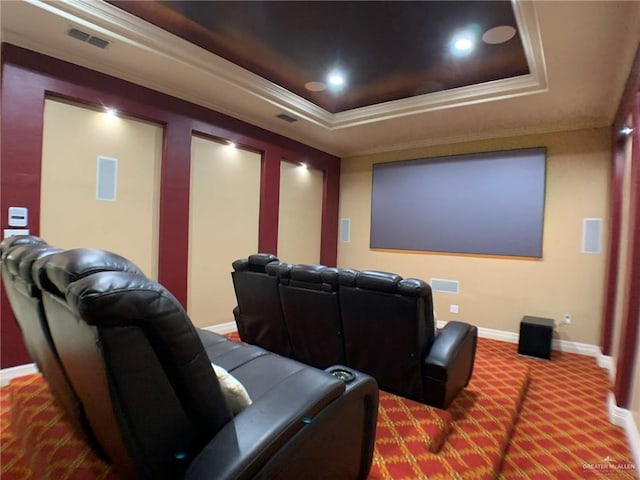 carpeted cinema featuring visible vents, crown molding, a tray ceiling, and baseboards
