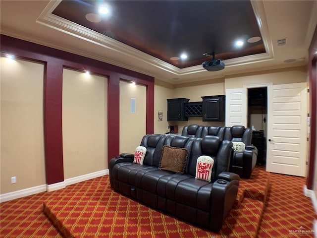 carpeted cinema room with a raised ceiling, crown molding, visible vents, and baseboards