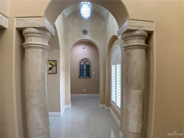corridor with ornate columns, arched walkways, and baseboards