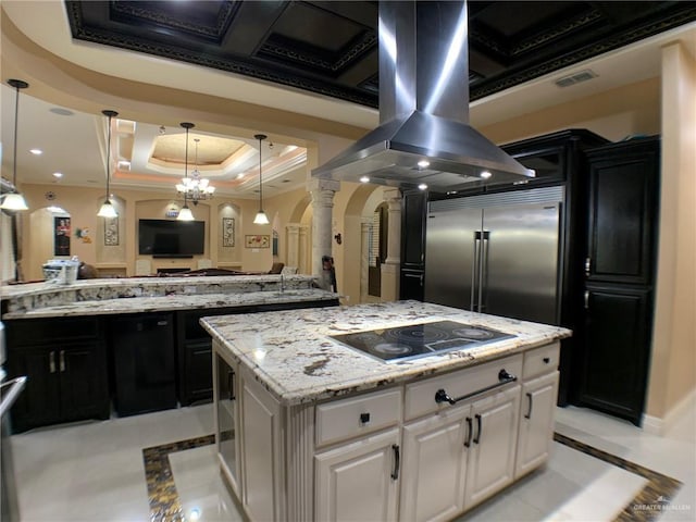 kitchen with black electric stovetop, a center island, arched walkways, decorative columns, and island exhaust hood