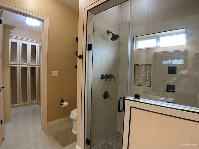 bathroom featuring baseboards, a stall shower, toilet, and tile patterned flooring