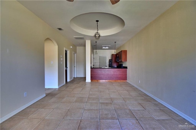 kitchen featuring a raised ceiling, hanging light fixtures, kitchen peninsula, and light tile patterned floors