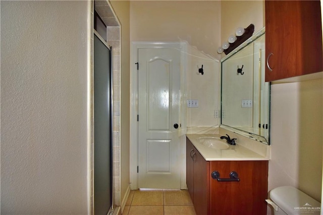 bathroom featuring tile patterned floors, toilet, a shower with door, and vanity