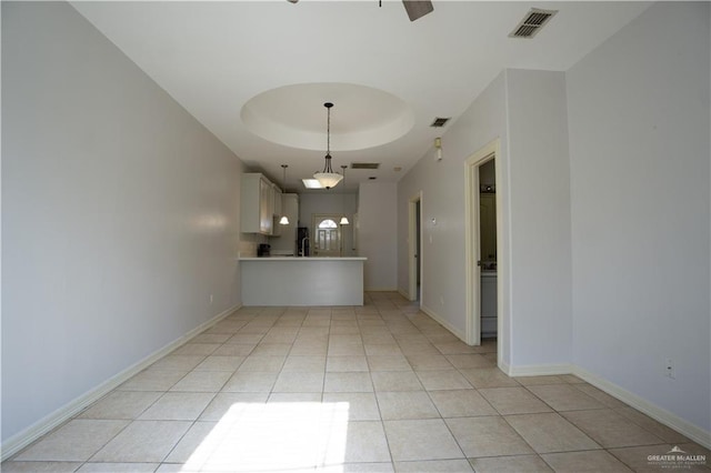 interior space with a tray ceiling and light tile patterned floors