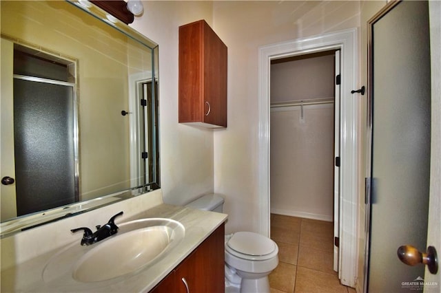 bathroom with tile patterned floors, toilet, a shower with door, and vanity