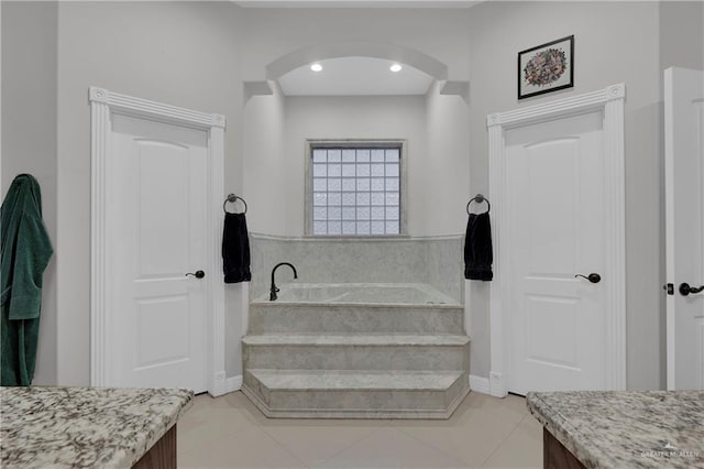 bathroom with tiled tub, vanity, and tile patterned floors