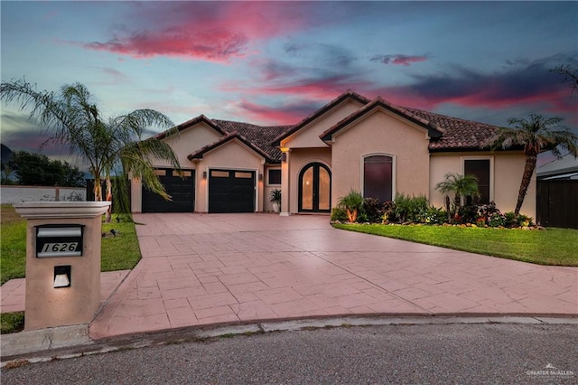 mediterranean / spanish-style home featuring a garage and a lawn