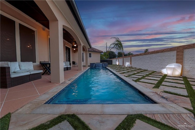 pool at dusk featuring outdoor lounge area and a patio area