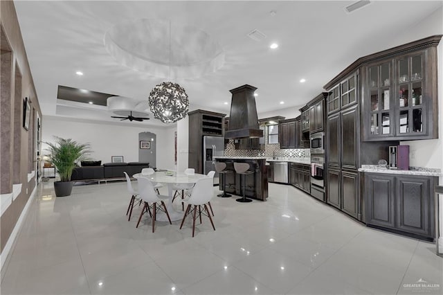 dining area with light tile patterned floors, ceiling fan, and a tray ceiling