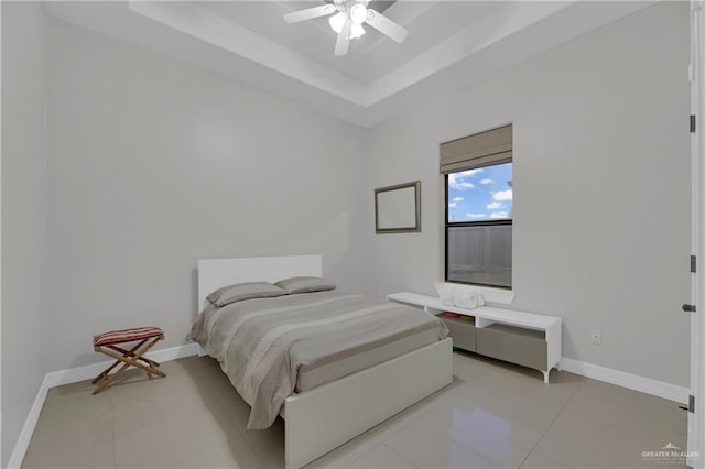 bedroom featuring light tile patterned flooring, ceiling fan, and a tray ceiling