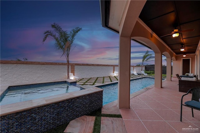 pool at dusk with an in ground hot tub, ceiling fan, and a patio