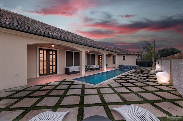 pool at dusk with french doors, an in ground hot tub, and a patio area