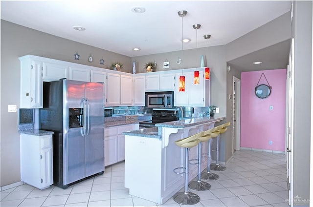 kitchen with a peninsula, stone countertops, white cabinetry, backsplash, and stainless steel appliances