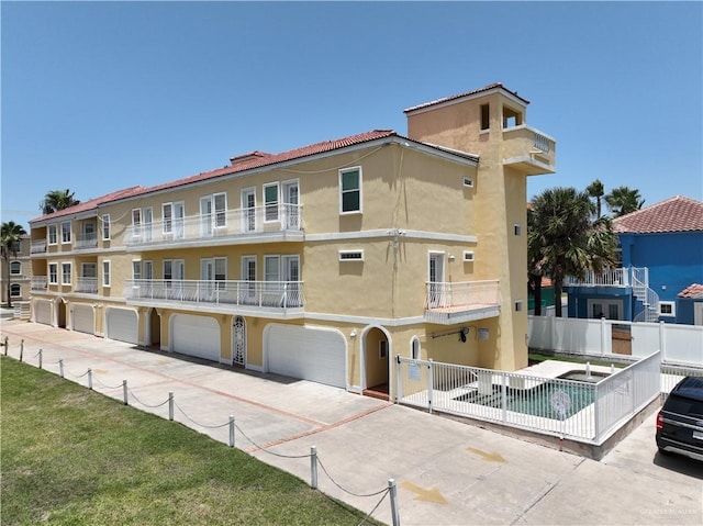 view of property featuring fence, an attached garage, and driveway