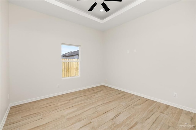 spare room featuring light hardwood / wood-style floors, a raised ceiling, and ceiling fan