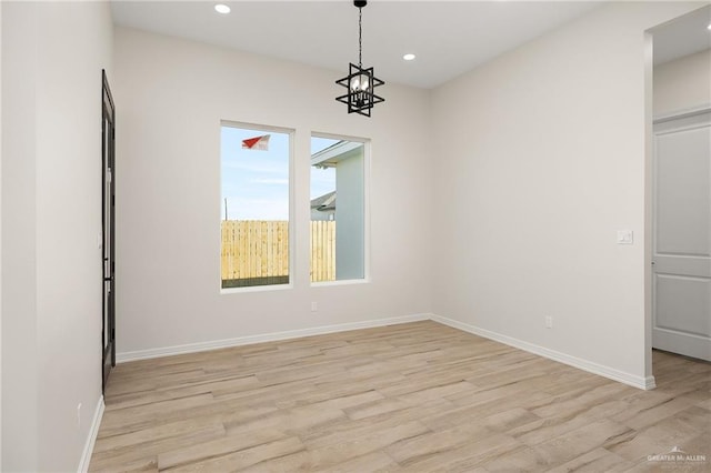 spare room featuring light hardwood / wood-style floors and an inviting chandelier