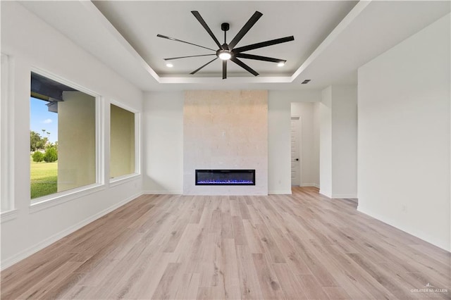 1114 Knotty Pine Ln, Harlingen, TX 78552 - unfurnished living room featuring a tray ceiling, light wood-style floors, a tile fireplace, a ceiling fan, and recessed lighting