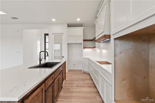 1114 Knotty Pine Ln, Harlingen, TX 78552 - kitchen with light wood finished floors, a kitchen island with sink, white cabinets, recessed lighting, and light stone countertops