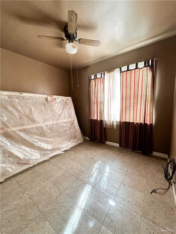 empty room with a textured ceiling, ceiling fan, and light tile patterned flooring