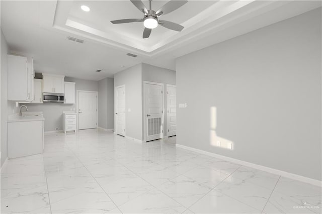 interior space featuring a raised ceiling, ceiling fan, and sink