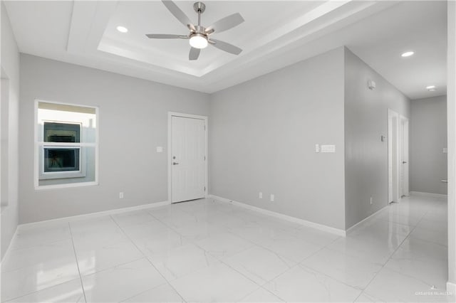 spare room with a raised ceiling and ceiling fan