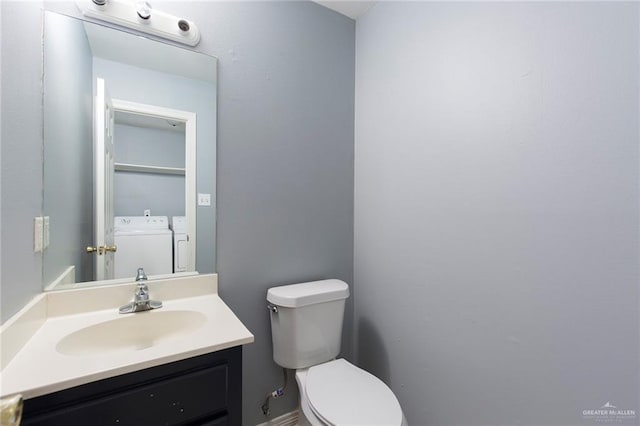 bathroom featuring vanity, separate washer and dryer, and toilet