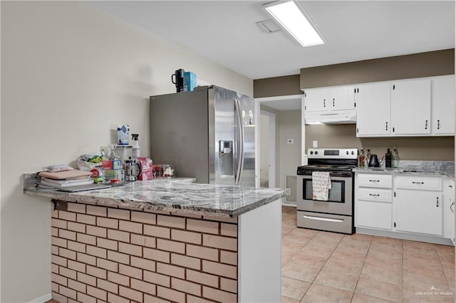 kitchen with appliances with stainless steel finishes, white cabinets, light tile patterned floors, light stone counters, and kitchen peninsula