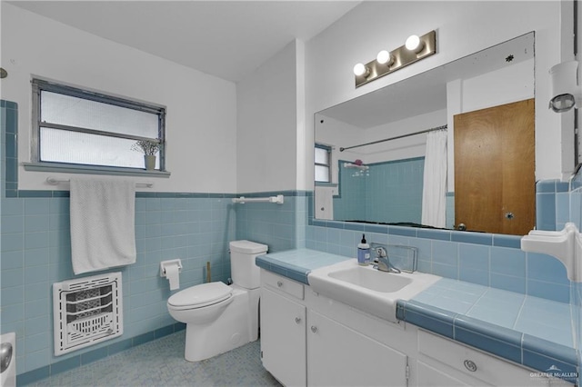 bathroom with toilet, heating unit, tile walls, vanity, and a shower with shower curtain