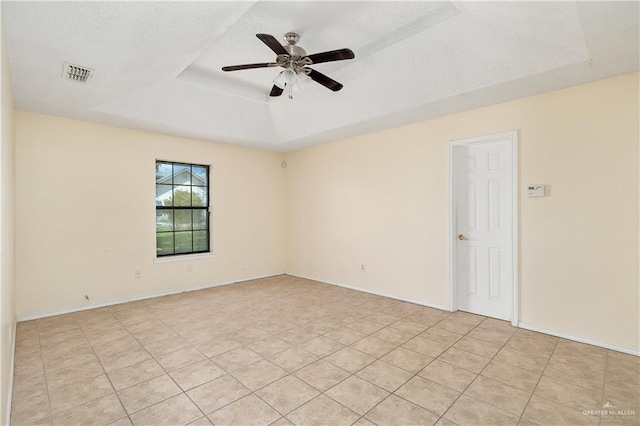 empty room featuring a tray ceiling, ceiling fan, and light tile patterned flooring