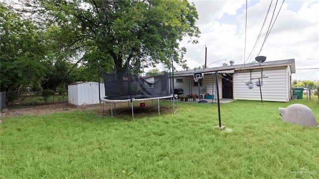 rear view of property with a yard, a trampoline, and a shed